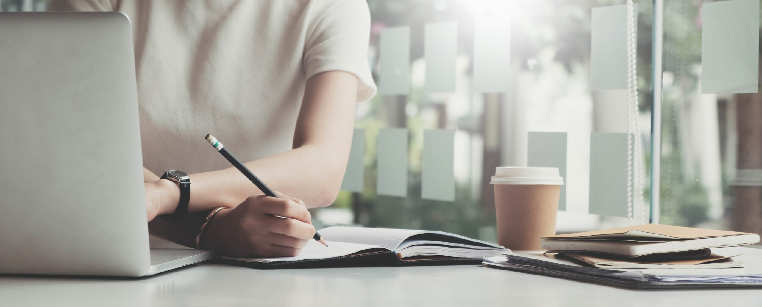 Une femme assise à son bureau qui remplit des documents manuellement