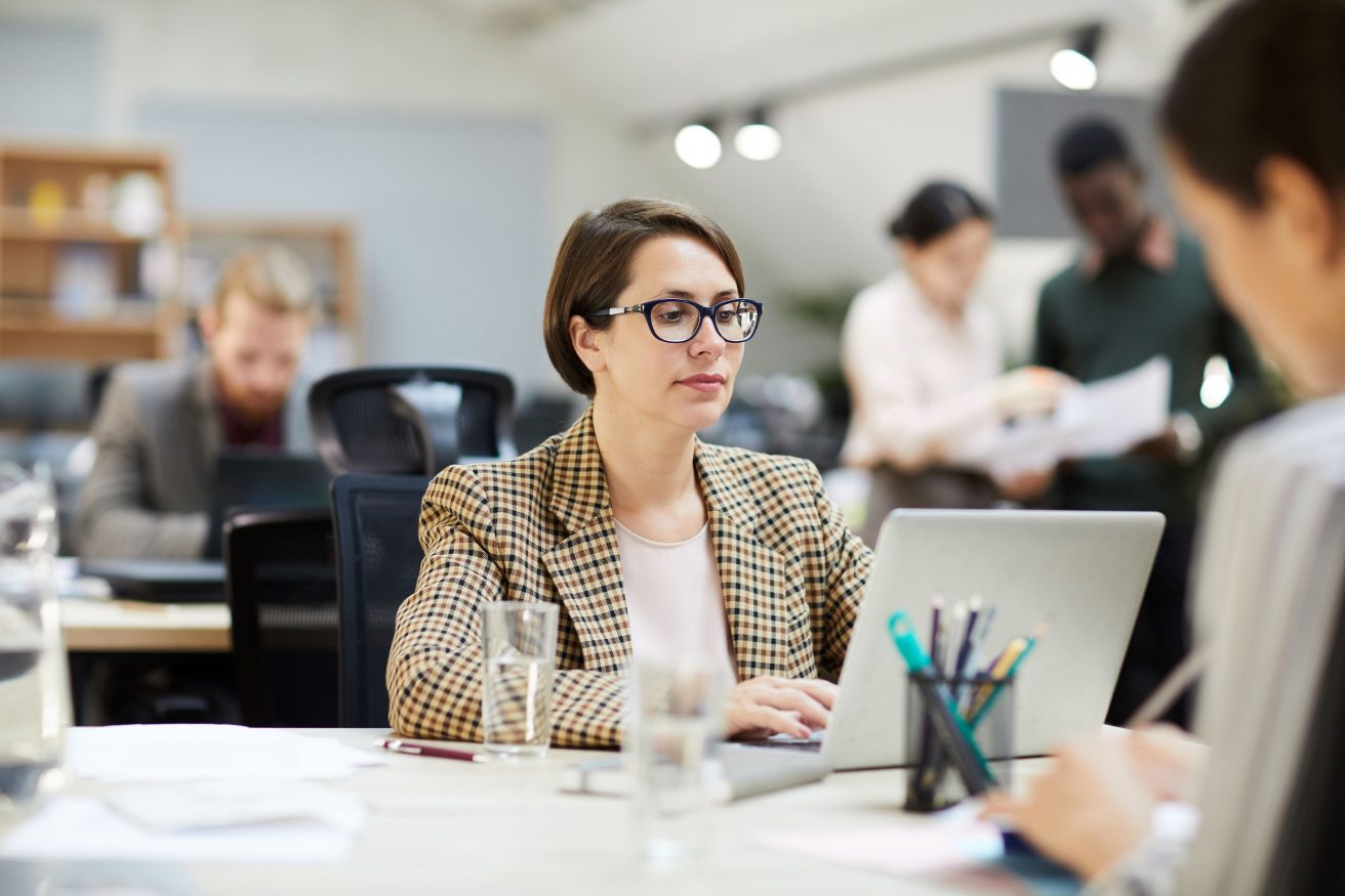1 expert comptable devant son poste de travail, au bureau avec des collègues autour